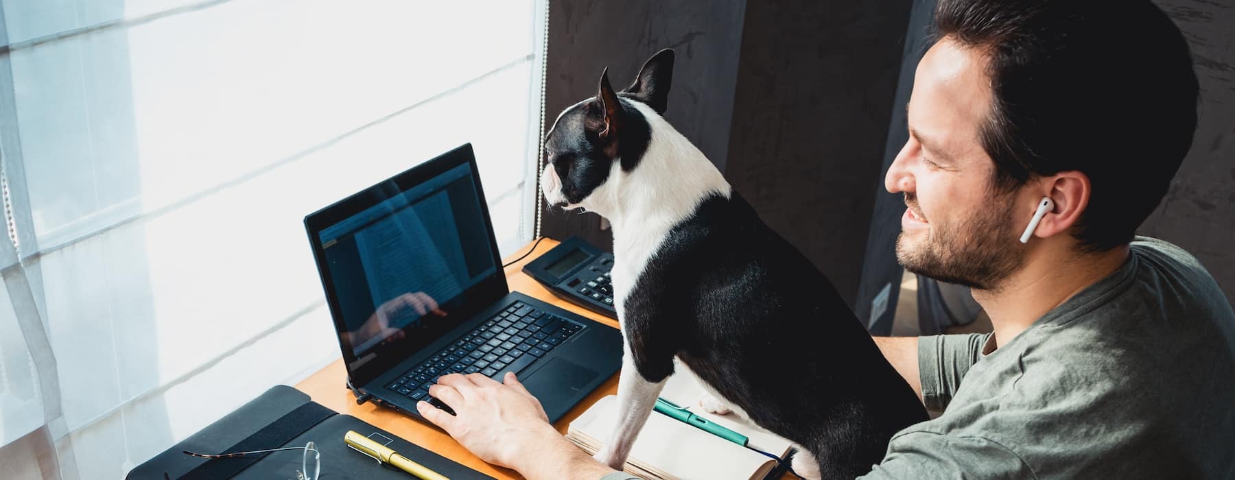 lifestyle image of a man working on his laptop with a dog in his lap